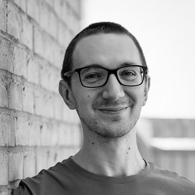 Andrew Lees, full stack engineer, smiling in front of a brick wall